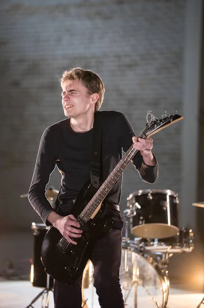 Un músico vestido de negro tocando emocionalmente la guitarra —  Fotos de Stock