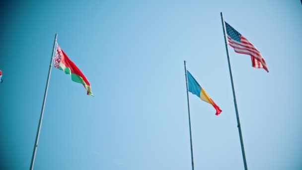 Banderas de los países del mundo que soplan en el viento sobre un fondo del cielo azul claro — Vídeo de stock