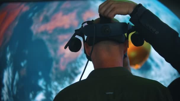 Exposição de Tecnologia - um homem coloca em um óculos VR com fones de ouvido — Vídeo de Stock