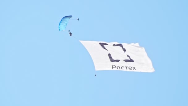 30 Ağustos 2019 Moskova, Rusya: Rostec logolu açık paraşüt ve bayrakla gökyüzünde uçan bir adam — Stok video