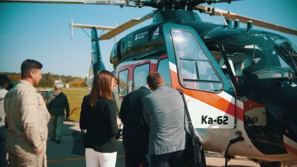 2019년 8월 30일 러시아 모스크바: 야외 항공기 전시회 - 헬리콥터 옆에 서서 가이드를 듣는 사람들 — 비디오