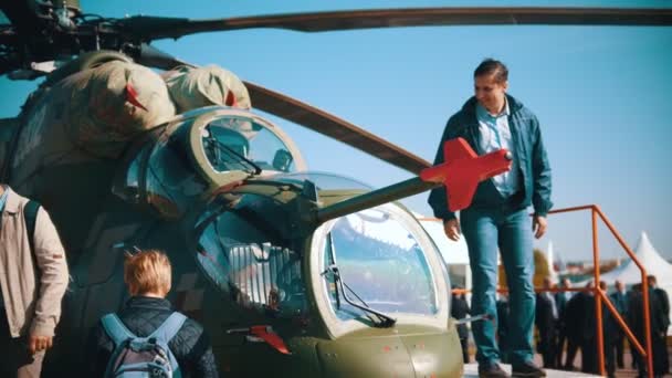 30. srpen 2019 Moskva, Rusko: venkovní expozice v letadle-mladí muži, kteří chodí kolem helikoptéry a dívají se na něj — Stock video