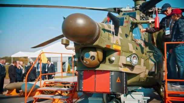 30 AGOSTO 2019 MOSCÚ, RUSIA: Una exposición de aviones al aire libre - personas caminando por la zona y mirando hacia arriba - un hombre de pie con un trabajador militar junto al helicóptero y escuchando la conferencia — Vídeos de Stock