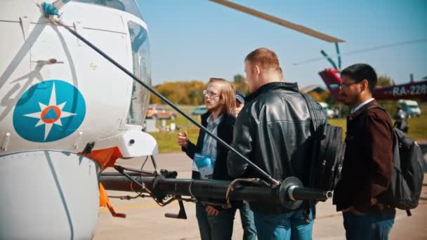 30 AGOSTO 2019 MOSCOW, RÚSSIA: Uma exposição de aeronaves ao ar livre - jovens em pé junto ao helicóptero e falando sobre isso — Vídeo de Stock