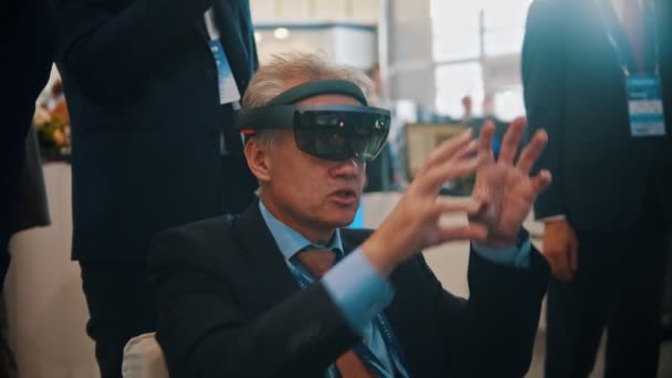 29 sierpnia 2019 Moskwa, Rosja: Wystawa technologii-Starzec siedzący w okularach VR i rozmawiający z kolegami — Wideo stockowe