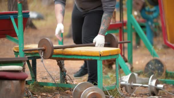 Trening kulturysta człowieka na zewnątrz boisko sportowe-zastępuje hantlami na stoisku — Wideo stockowe