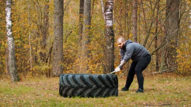 Un grande bodybuilder uomo colpire il pneumatico camion - foresta autunno — Video Stock