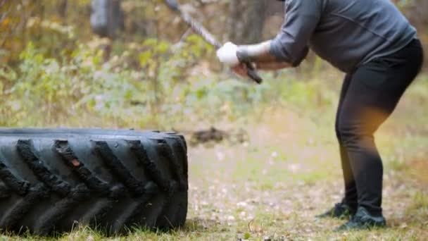 금속 망치로 트럭 타이어를 치는 힘든 수염 남자 보디 - 가을 숲 — 비디오
