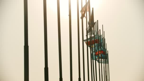 Banderas de los países del mundo que soplan en el viento en el fondo de la puesta del sol temprana — Vídeos de Stock