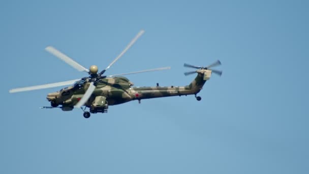 29 augusti 2019 Moskva, Ryssland: en militär mörkgrön kamouflage färg helikopter flyger i den blå himmel-utför piruetter — Stockvideo