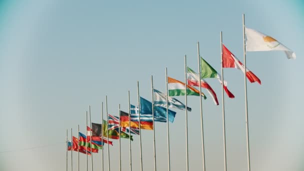 Banderas de los países del mundo que soplan en el viento en el fondo del cielo claro y hermoso — Vídeo de stock