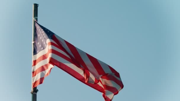 Bandeira dos EUA soprando no vento no fundo do céu azul claro — Vídeo de Stock