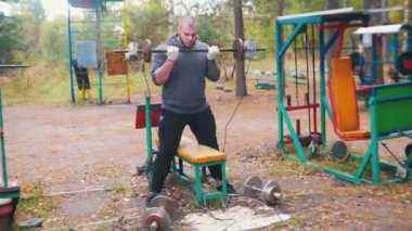 Bir dövmeli adam vücut geliştirmeci tuğla ve ağırlıklar yapılmış dumbbells ile ellerini pompalama - açık spor zemin eğitim - sonbahar ormanı