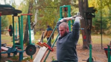 Bir dövmeli adam vücut geliştirmeci arkasında dumbbell ile ellerini pompalama - çocuklar spor zemin eğitim