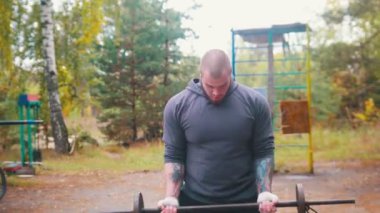Bir dövmeli adam vücut geliştirmeci küçük dumbbell ile ellerini pompalama - açık spor zemin eğitim - sonbahar ormanı