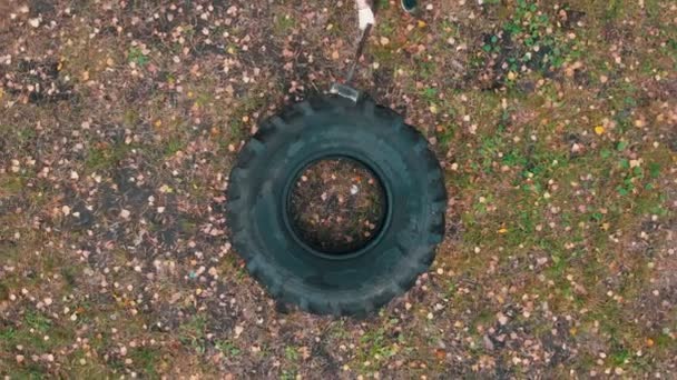 Duro hombre tatuado culturista golpeando el neumático del camión con un martillo - entrenamiento en el bosque de otoño — Vídeo de stock