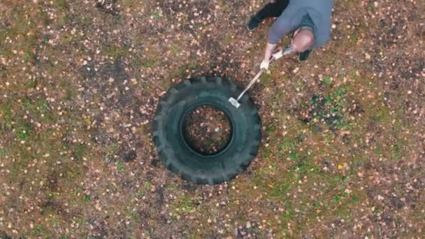 Tätowierter Mann schlägt mit Hammer auf LKW-Reifen ein - Training im Herbstwald — Stockvideo