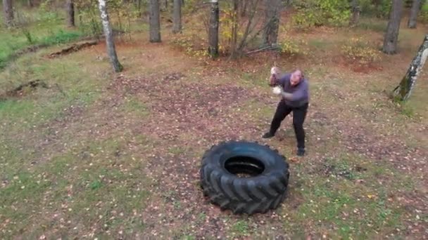 Karosseriebauer schlägt mit schwerem Eisenhammer auf LKW-Reifen ein - Reifenhämmern - Training im Herbstwald — Stockvideo