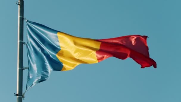 Bandera de Rumania ondeando en el viento sobre el fondo del cielo azul claro — Vídeos de Stock