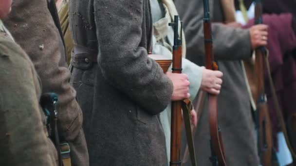 Солдаты в пальто стоят в ряд, держа в руках оружие - хлопают замерзшими руками — стоковое видео