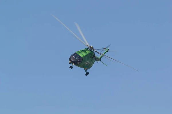 29 августа 2019 г. Москва, Россия: Военный ярко-зеленый вертолет, летящий в голубом небе - вид спереди — стоковое фото