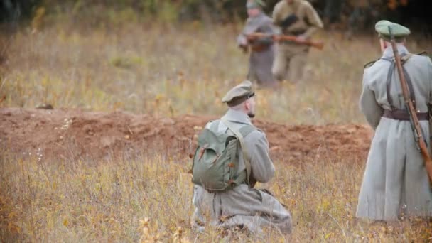 RÚSSIA, REPÚBLICA DO TATARSTÃO 30-09-2019: Uma reconstrução das operações militares na Rússia em 1917 - soldados de casacos correndo no campo de outono - um homem em primeiro plano se levantando e se juntando a eles — Vídeo de Stock