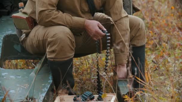 Voják připraví munici pro nálož do kulometu - zasune kulky do děr — Stock video