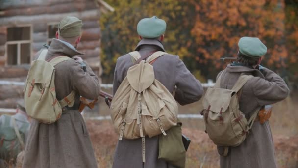 Τρεις στρατιώτες στέκονται στο πεδίο της μάχης και σημαδεύουν κάτι με όπλα. — Αρχείο Βίντεο