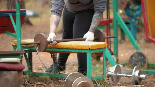 En man kroppsbyggare tar hantlarna på läktaren — Stockfoto