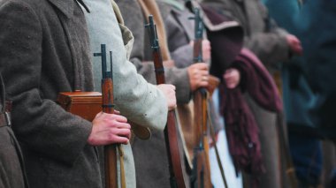 Birkaç asker ellerinde silah ve kalın giysilerle birbirlerine yakın duruyorlar.