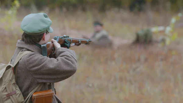 A military man is ready to shoot right on the field near other soldiers — Stock Photo, Image