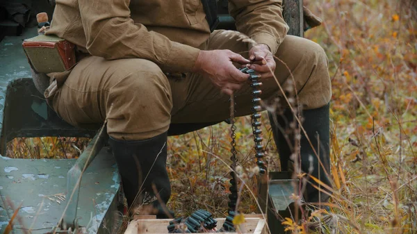 Солдат готовит боеприпасы для зарядки пулемёта - вставляет пули в отверстия — стоковое фото