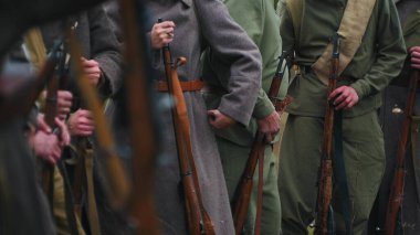 Savaş giysisi giymiş birkaç asker ellerinde silahlarla birbirlerine yakın duruyorlar..