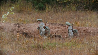 Silahlı iki asker sipere giriyor.