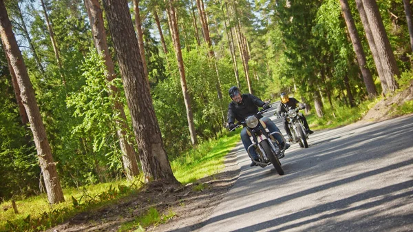 Dos motociclistas viajan uno por el otro a lo largo de la carretera en el bosque —  Fotos de Stock