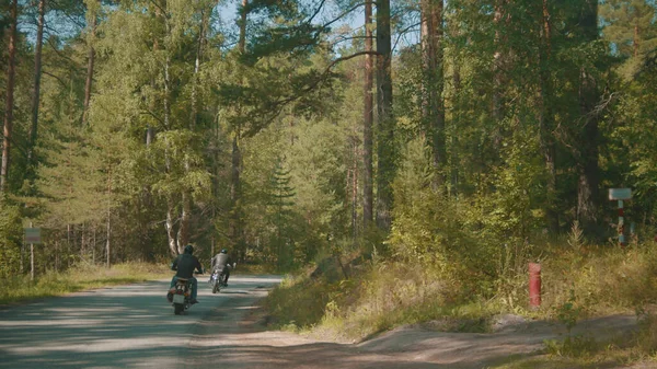 Motociclistas estão montando uma estrada empoeirada na floresta — Fotografia de Stock