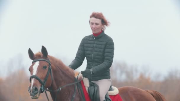 Dos mujeres montando caballos de bahía sosteniéndolos por las riendas — Vídeo de stock