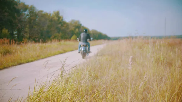 Motociclista está andando de bicicleta na estrada perto do campo — Fotografia de Stock