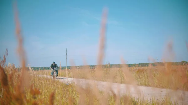 Один байкер едет по дороге на поле — стоковое фото