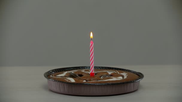 Свеча гаснет на одиноком торте. — стоковое видео