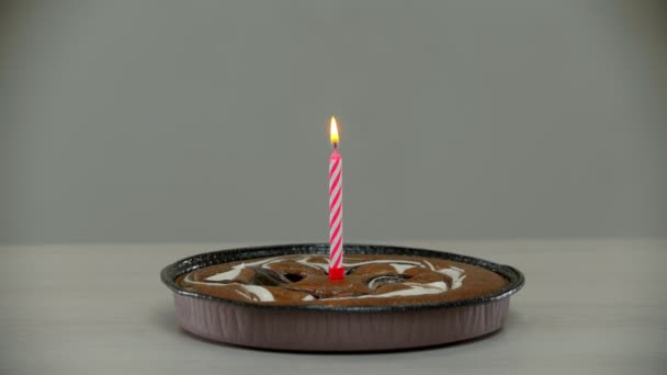 Свеча гаснет на одиноком торте на столе. — стоковое видео