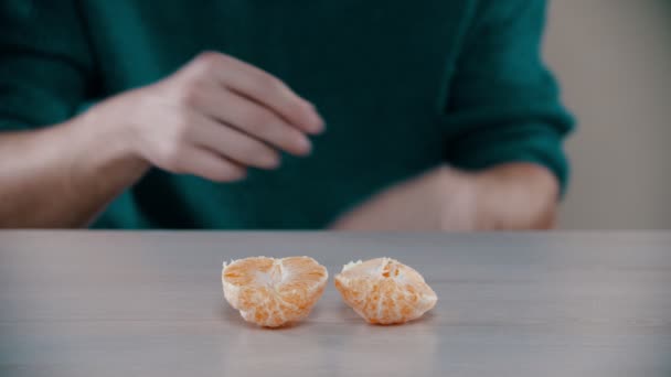 Un hombre está rompiendo en pedazos una naranja madura — Vídeo de stock