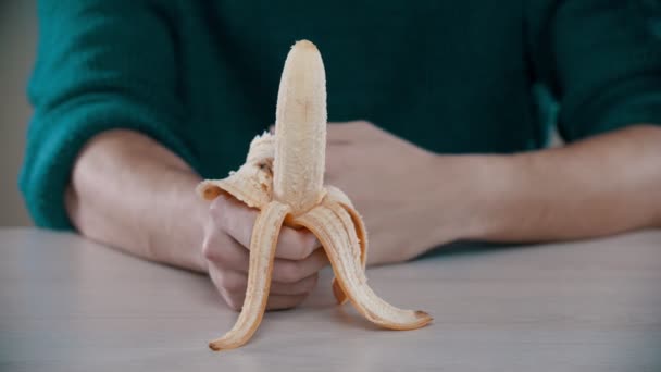 Мужчина ест очищенный банан — стоковое видео