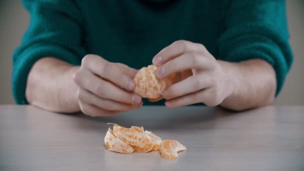 Un hombre está rompiendo en pedazos una naranja madura sobre la mesa — Vídeo de stock