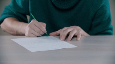A man is actively writing word on a paper and crumplng it