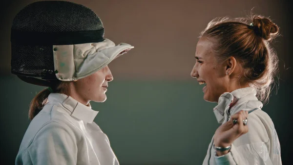 Два молодых и красивых фехтовальщика в шлеме смотрят друг на друга и улыбаются — стоковое фото