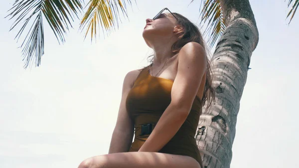 Une jeune femme se tient près d'un palmier — Photo
