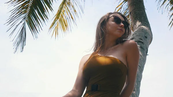 Молодая и красивая женщина стоит рядом с пальмой — стоковое фото