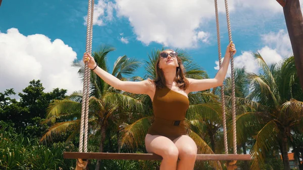 Menina bonita está montando em um balanço na praia — Fotografia de Stock