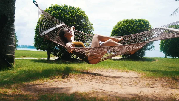 Menina bonita dorme em uma rede sob o sol — Fotografia de Stock